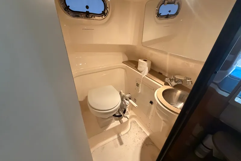 Slide: The Image of 2008 Pursuit OS 285 Offshore boat bathroom with toilet, sink, and porthole windows. - 21