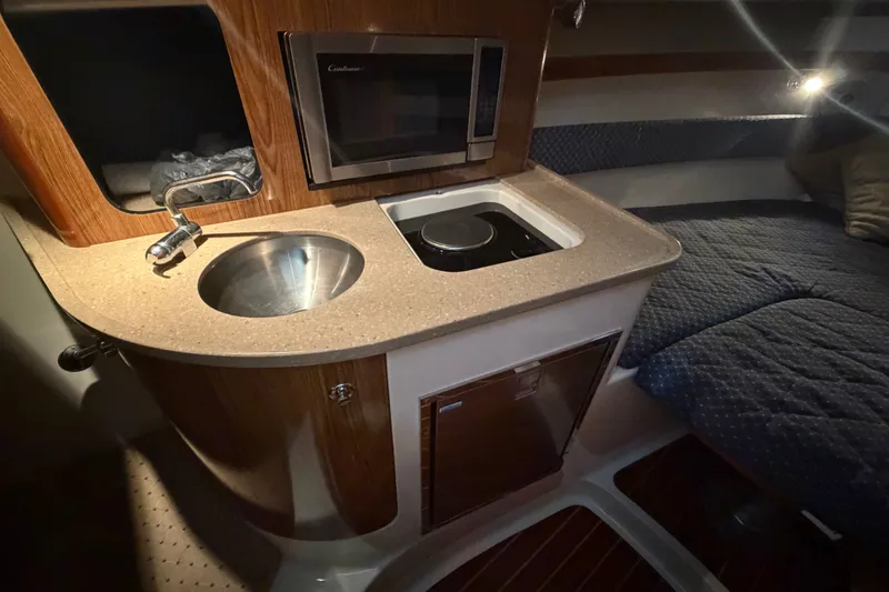Slide: The Image of 2008 Pursuit OS 285 Offshore cabin with kitchenette, sink, microwave, and cozy sleeping area. - 19