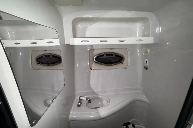Slide: The Image of 2005 Crownline 270 CR boat bathroom with sink, mirror, and porthole window. - 44