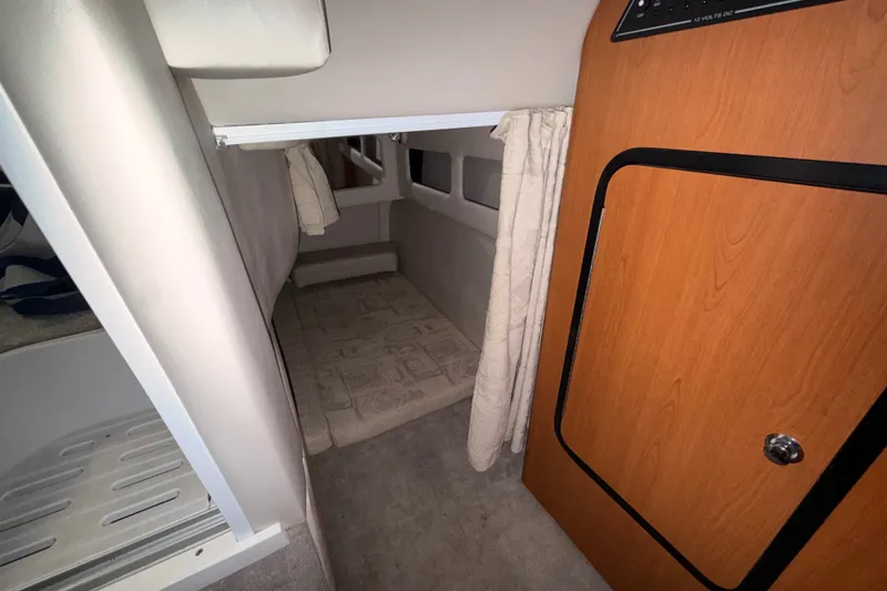 Slide: The Image of 2005 Crownline 270 CR cabin interior with cozy sleeping area and wooden door. - 48