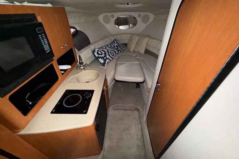 Slide: The Image of 2005 Crownline 270 CR cabin interior with kitchenette, sink, and cozy seating area. - 30