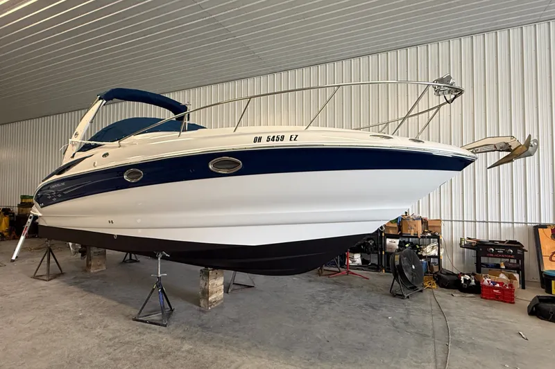 The Image of 2005 Crownline 270 CR boat in storage, elevated on stands, in a garage setting. - 0