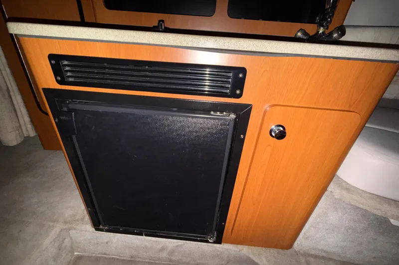 Slide: The Image of 2005 Crownline 270 CR boat interior with wooden cabinetry and built-in refrigerator. - 38