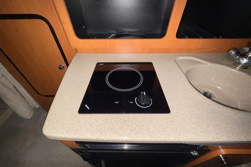 Slide: The Image of Compact kitchen area in a 2005 Crownline 270 CR boat with stovetop and sink. - 41