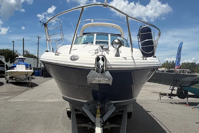 Slide: The Image of 2006 Sea Ray 300 Sundancer boat on trailer under a cloudy sky at a dealership. - 7