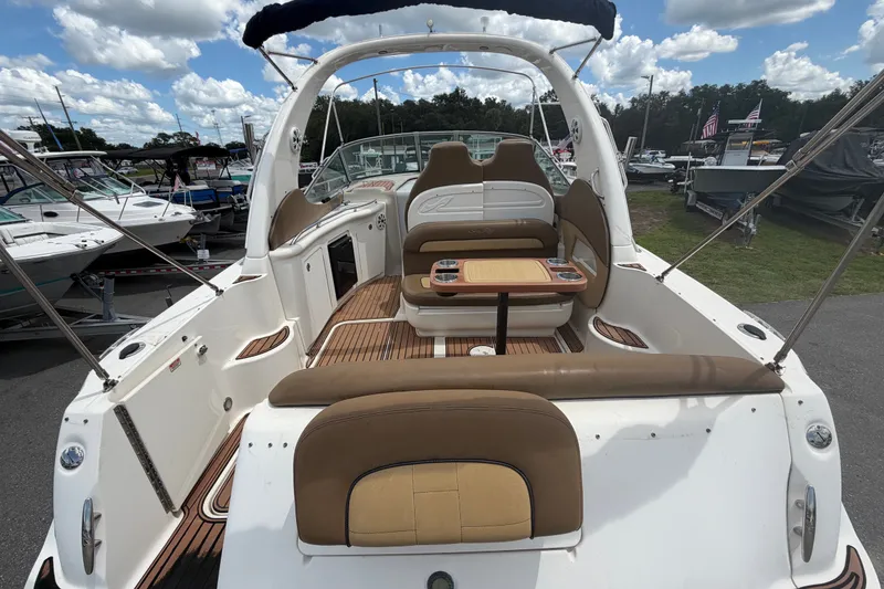 Slide: The Image of 2006 Sea Ray 300 Sundancer boat interior with seating and table, docked under a cloudy sky. - 9