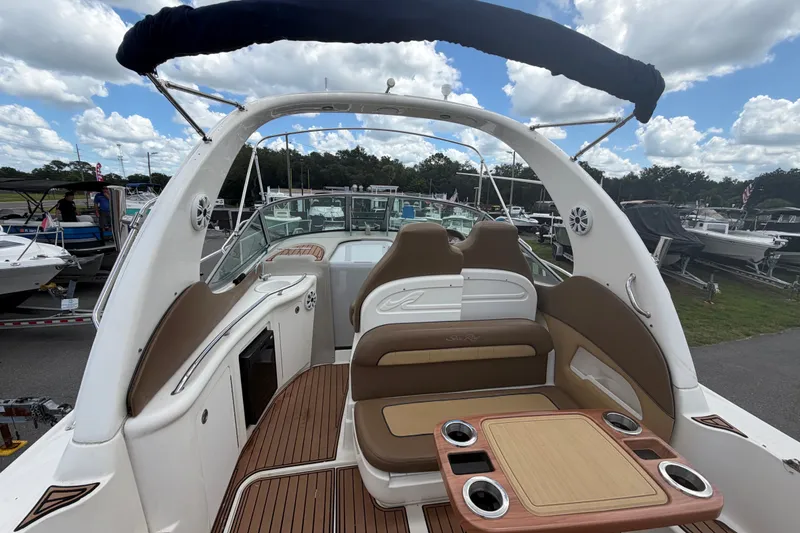 Slide: The Image of 2006 Sea Ray 300 Sundancer boat interior with seating and table, docked under a cloudy sky. - 11