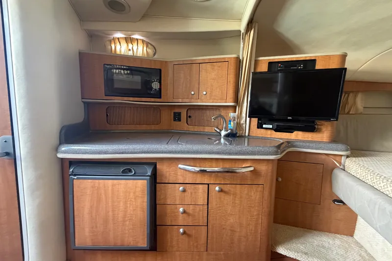 Slide: The Image of 2006 Sea Ray 300 Sundancer interior with kitchenette, microwave, TV, and compact fridge. - 22