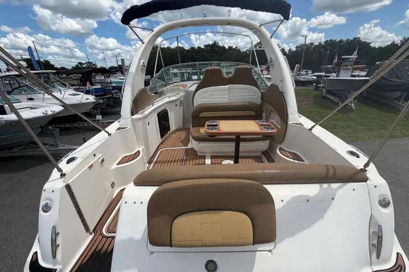 Slide: The Image of 2006 Sea Ray 300 Sundancer boat interior with seating and table, docked under a cloudy sky. - 8