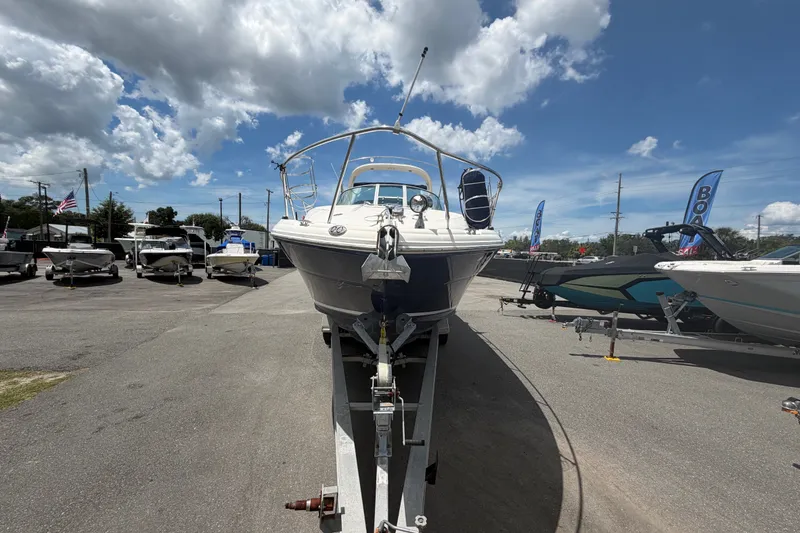 Slide: The Image of 2006 Sea Ray 300 Sundancer boat on trailer under a cloudy sky at a dealership. - 7
