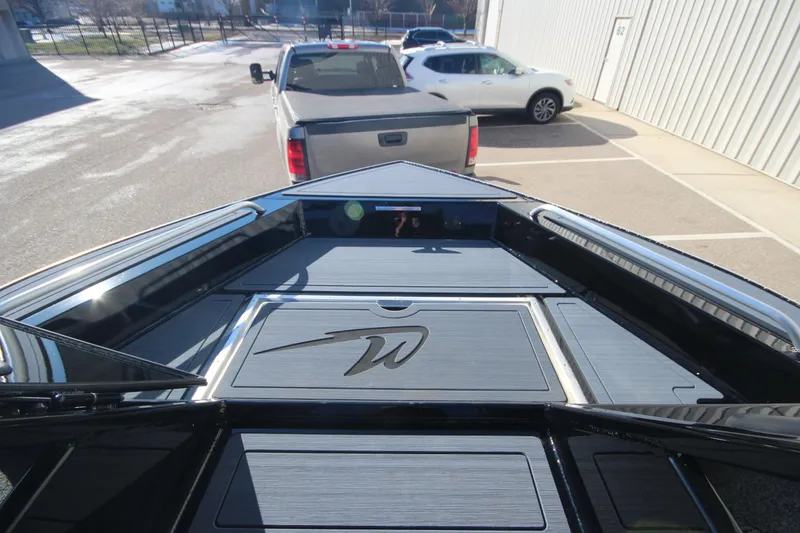 Slide: The Image of 2025 Weldcraft 210 Revolution Soft Top boat, viewed from the bow, parked near trucks. - 21