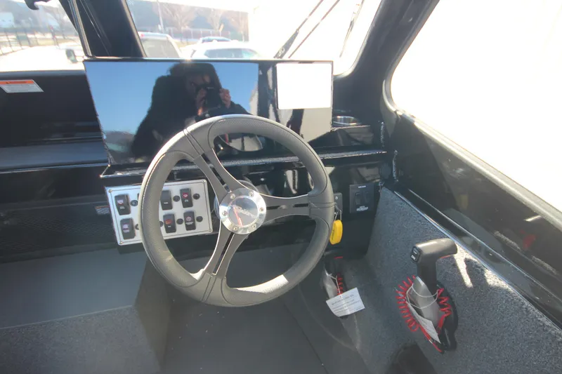 Slide: The Image of 2025 Weldcraft 210 Revolution Soft Top boat interior with steering wheel and control panel. - 18