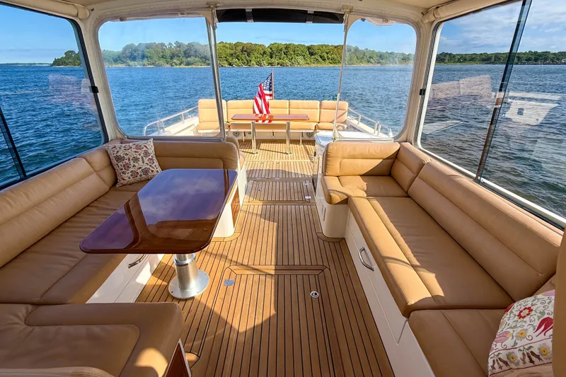 Slide: The Image of Luxurious 2017 MJM 50z yacht interior with tan seating and wooden flooring on a serene lake. - 48