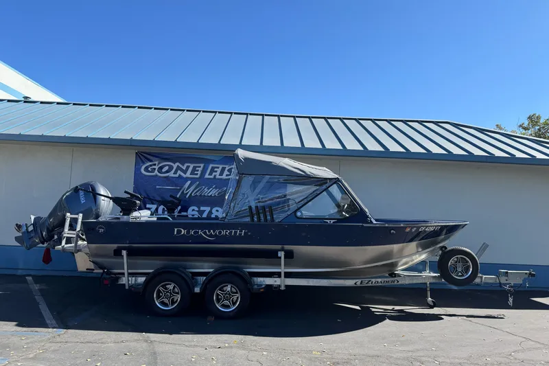 The Image of 2025 Duckworth 20 Advantage boat on trailer, parked outside a building under clear blue sky. - 1