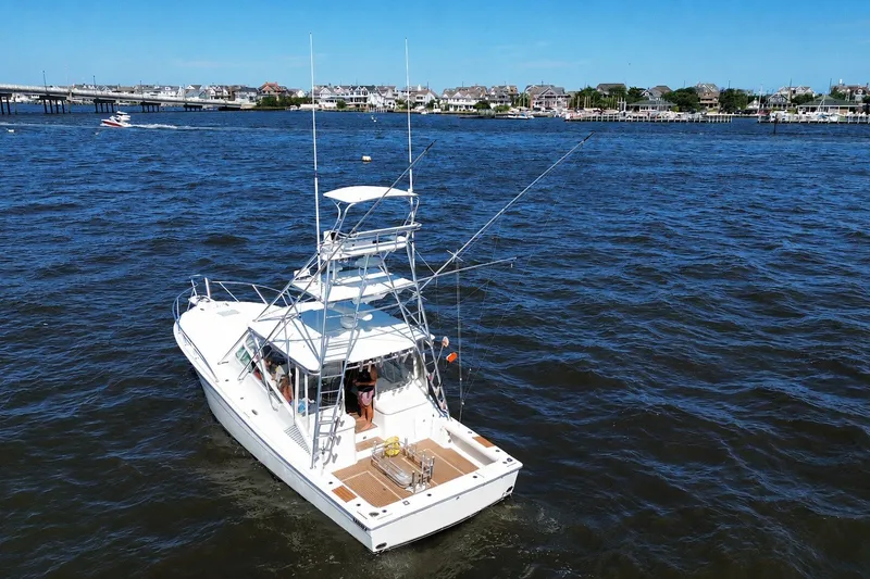 Slide: The Image of 2006 Topaz 40 Express boat on water, with people onboard, near coastal town. - 12