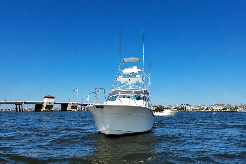 Slide: The Image of 2006 Topaz 40 Express boat on water near bridge, clear blue sky. - 5