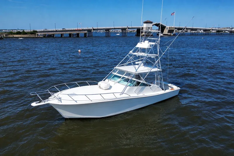 Slide: The Image of 2006 Topaz 40 Express boat on water near a bridge under clear blue sky. - 1