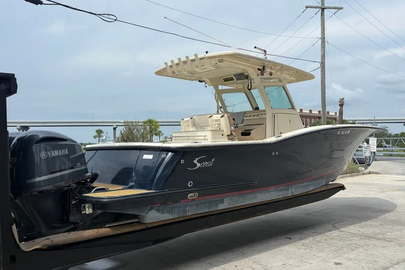 The Image of 2014 Scout 320 LXF boat with Yamaha engine on a lift, near a bridge. - 1