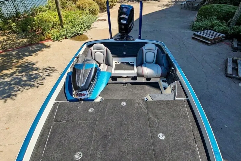 Slide: The Image of 2014 Ranger Z518 Comanche boat interior with seating and motor, parked outdoors. - 13