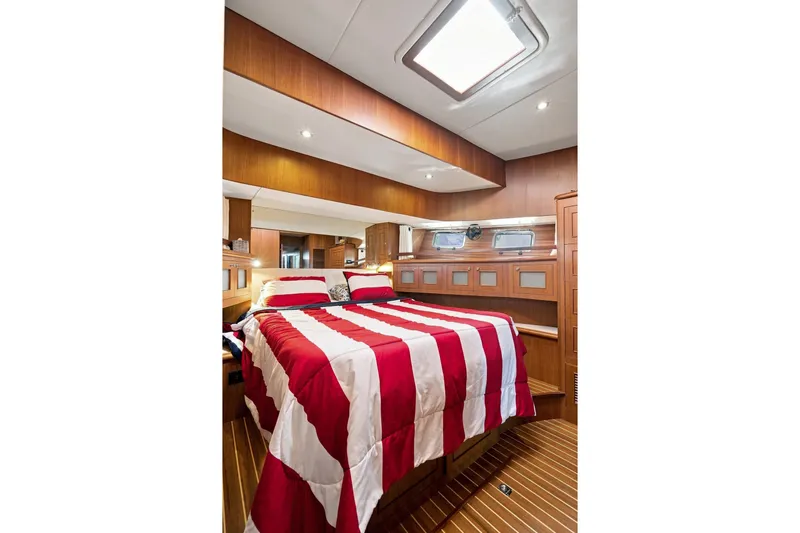 Slide: The Image of Luxurious 2015 North Pacific NP49 yacht bedroom with striped bedding and wooden interior. - 21