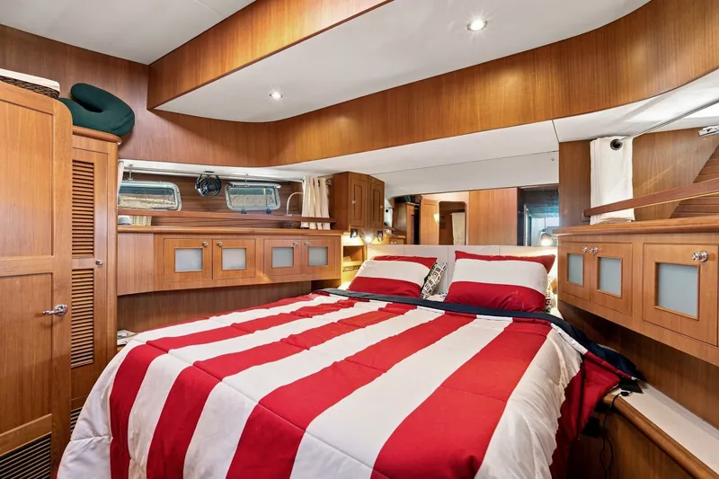 Slide: The Image of Luxurious 2015 North Pacific NP49 yacht bedroom with striped bedding and wooden cabinetry. - 22