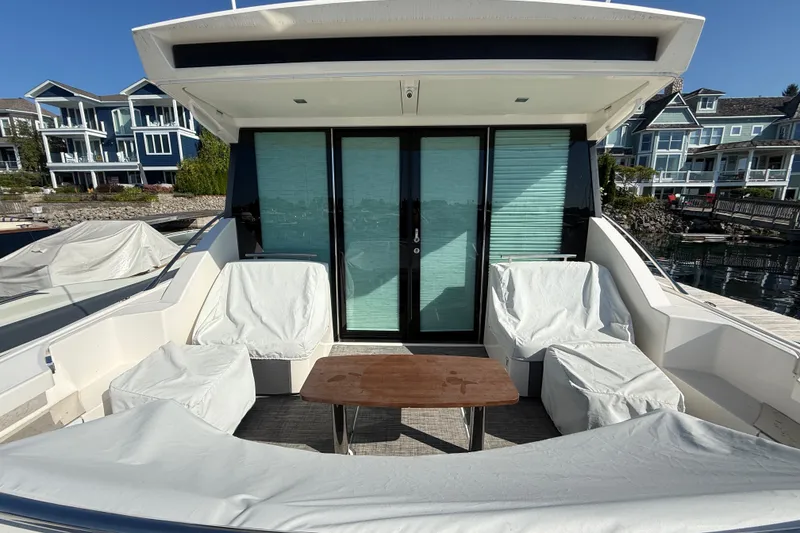 Slide: The Image of 2015 Tiara Yachts C44 Coupe with covered seating area and table, docked near waterfront homes. - 46