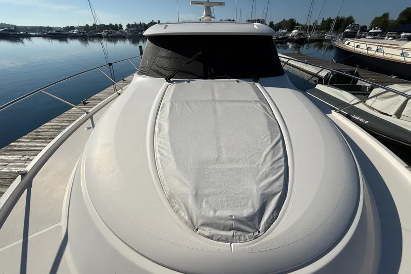 Slide: The Image of 2015 Tiara Yachts C44 Coupe docked at marina, showcasing sleek design and covered deck. - 44