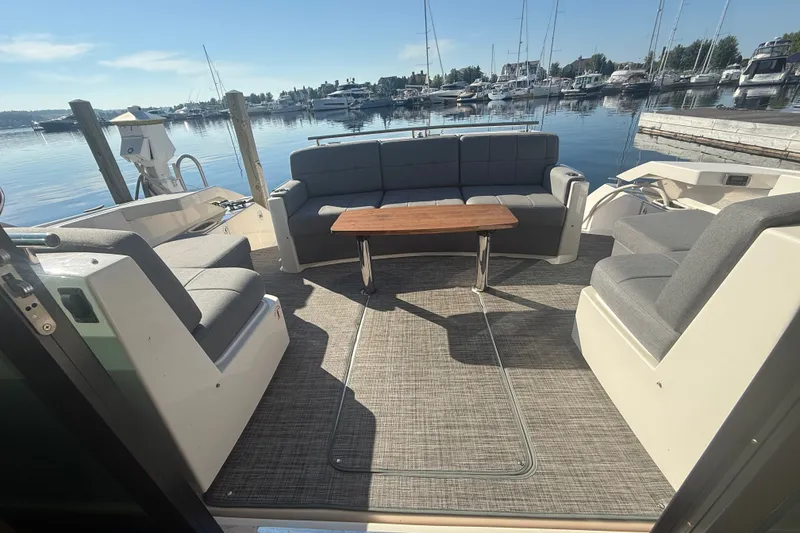 Slide: The Image of 2015 Tiara Yachts C44 Coupe cockpit with plush seating and wooden table, docked at marina. - 42
