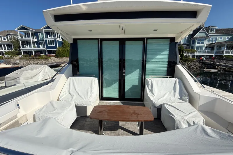 Slide: The Image of 2015 Tiara Yachts C44 Coupe with covered seating and table on deck, docked near waterfront homes. - 45