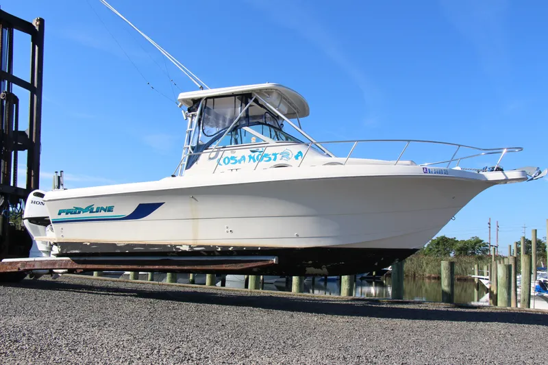 Slide: The Image of 1996 Pro-Line 2950 Walkaround boat on trailer, dockside, under clear blue sky. - 14
