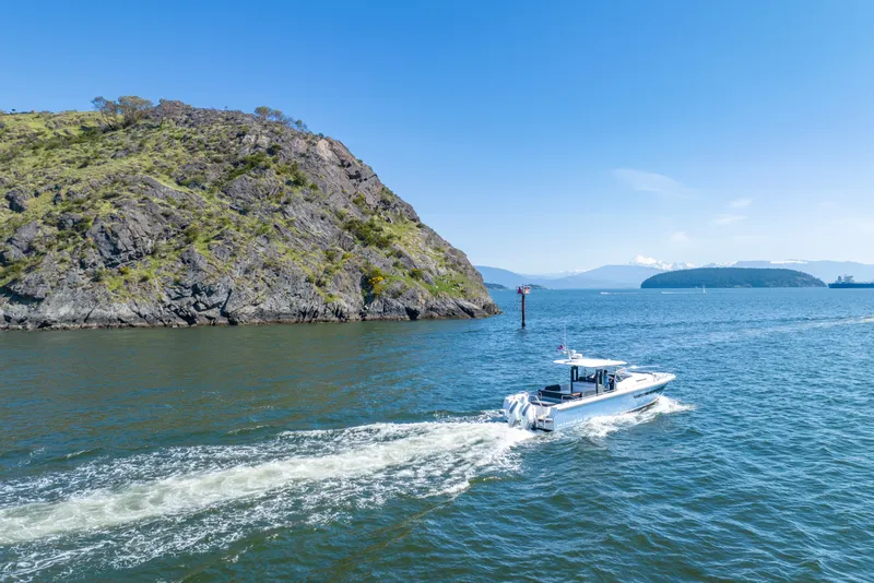 Slide: The Image of 2023 Nimbus Tender 11 cruising near rocky coastline under clear blue sky. - 12