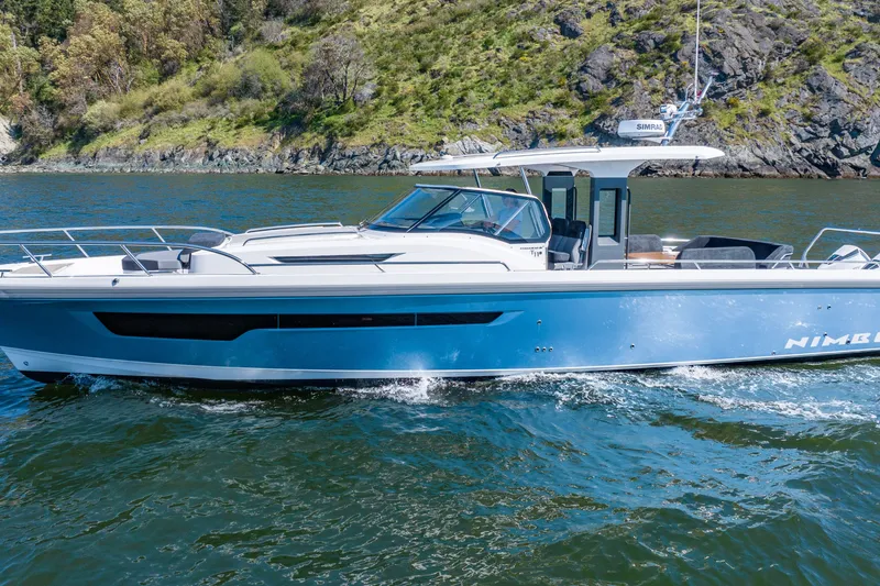 The Image of 2023 Nimbus Tender 11 boat cruising on a scenic lake with rocky shoreline. - 0