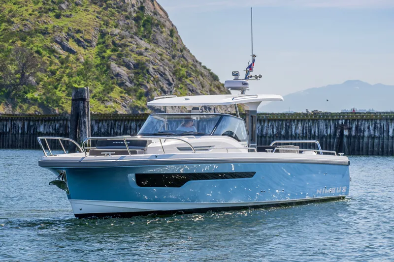 Slide: The Image of 2023 Nimbus Tender 11 boat cruising on a sunny day near a rocky shoreline. - 8