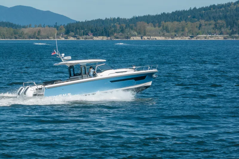 Slide: The Image of 2023 Nimbus Tender 11 cruising on a scenic lake with forested hills in the background. - 13