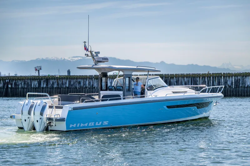 Slide: The Image of 2023 Nimbus Tender 11 boat cruising on calm water near a dock. - 1