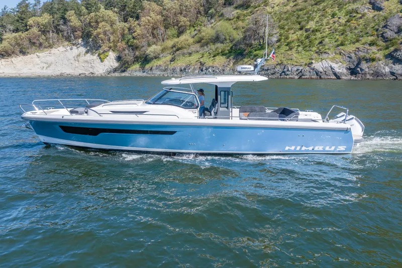 Slide: The Image of 2023 Nimbus Tender 11 boat cruising on scenic waterway with lush green shoreline. - 19