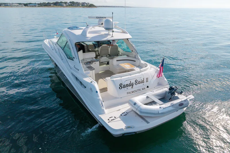 Slide: The Image of 2006 Sea Ray 48 Sundancer yacht on calm waters, featuring a small dinghy and American flag. - 35