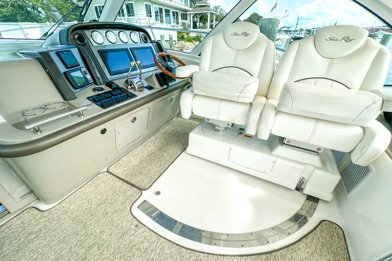 Slide: The Image of 2006 Sea Ray 48 Sundancer helm with dual white captain chairs and advanced navigation controls. - 55