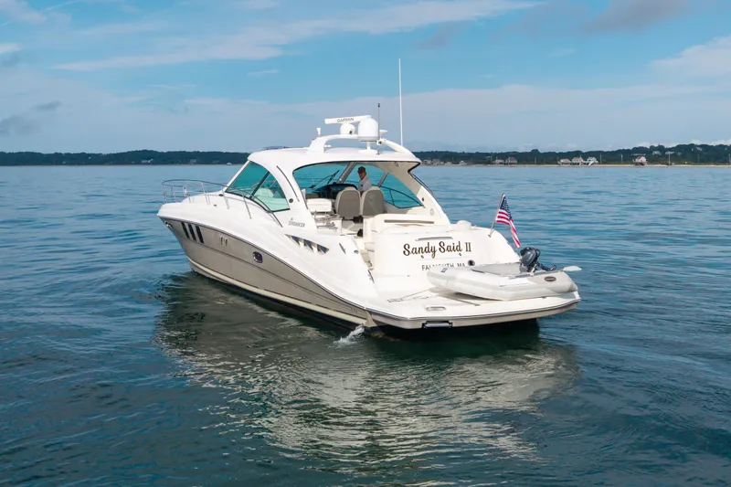 Slide: The Image of 2006 Sea Ray 48 Sundancer yacht on calm water, rear view with American flag. - 12