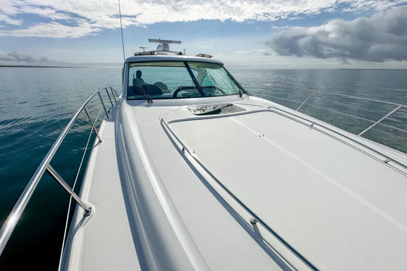 Slide: The Image of 2006 Sea Ray 48 Sundancer yacht cruising on calm ocean waters under a partly cloudy sky. - 59