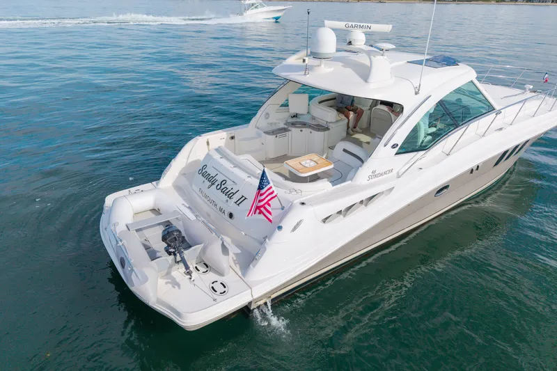 Slide: The Image of 2006 Sea Ray 48 Sundancer yacht on calm water, featuring spacious deck and American flag. - 34