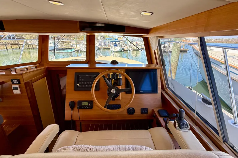 Slide: The Image of Interior view of 2015 Coastal Craft 45 yacht helm with wooden finish and marina view. - 50