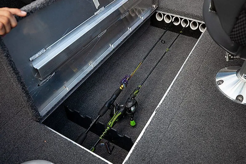 Slide: The Image of 2027 Lowe Fishing Machine 1625SC rod storage compartment with fishing rods and carpeted interior. - 5