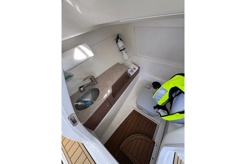 Slide: The Image of Interior of 2022 Boston Whaler 280 Vantage boat, featuring a compact bathroom with sink and toilet. - 19