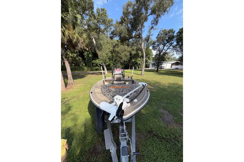 Slide: The Image of 2025 Mako 18 Pro Skiff Backwater Edition boat on trailer, parked on grassy area. - 5
