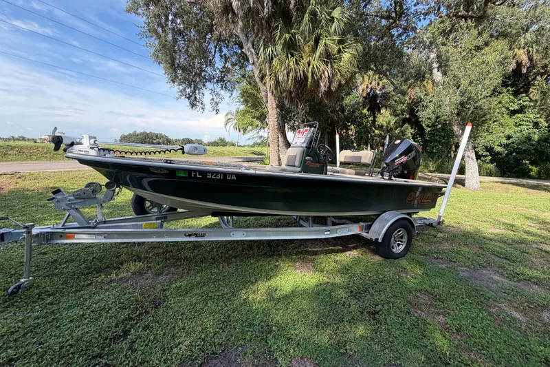 The Image of 2025 Mako 18 Pro Skiff Backwater Edition boat on trailer, parked on grassy area. - 1