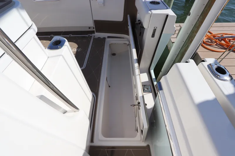 Slide: The Image of 2021 Edgewater 370CC boat interior with open storage compartment and cup holders. - 20