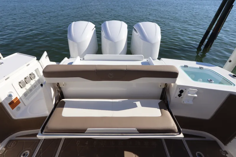 Slide: The Image of 2021 Edgewater 370CC boat with triple engines and comfortable seating, docked on calm water. - 13