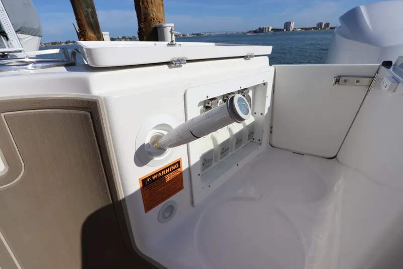 Slide: The Image of Edgewater 370CC 2021 boat deck with utility panel and warning label, overlooking water. - 8