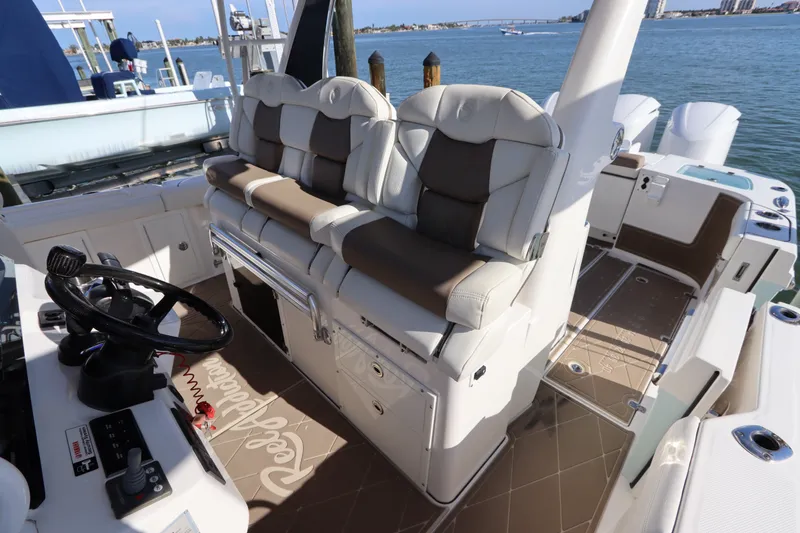 Slide: The Image of 2021 Edgewater 370CC boat interior with plush seating and steering wheel, docked by the water. - 30